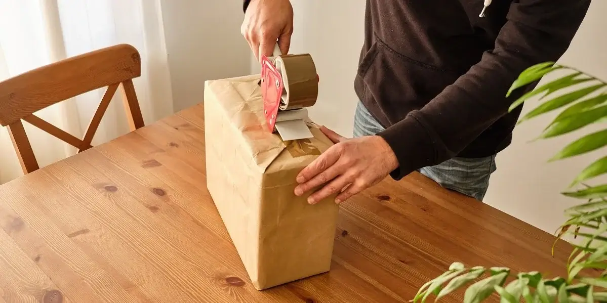 A person carefully packaging a poster for shipment